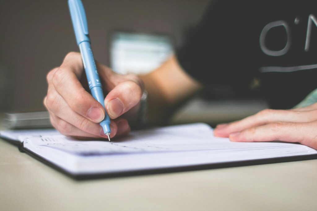 pexels photo 210661 210661 Close-up of hand writing in notebook using a blue pen, focus on creativity.