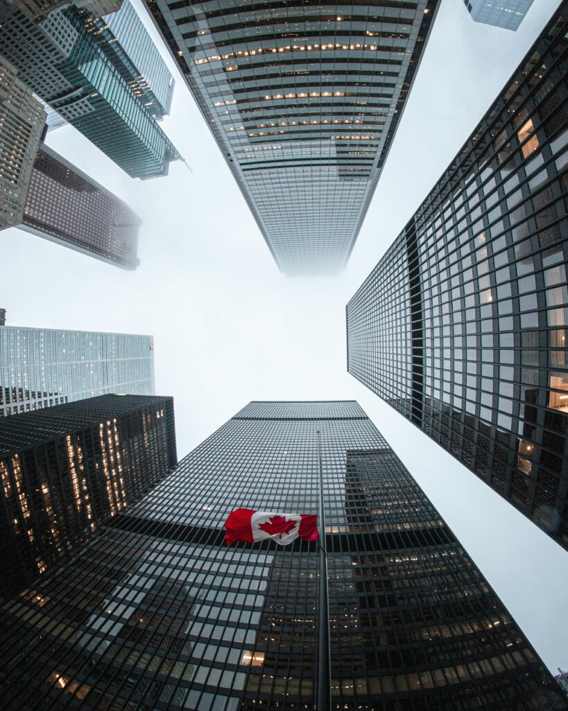 pexels photo 3727074 3727074 Looking up at Toronto skyscrapers with a Canadian flag on a cloudy day.