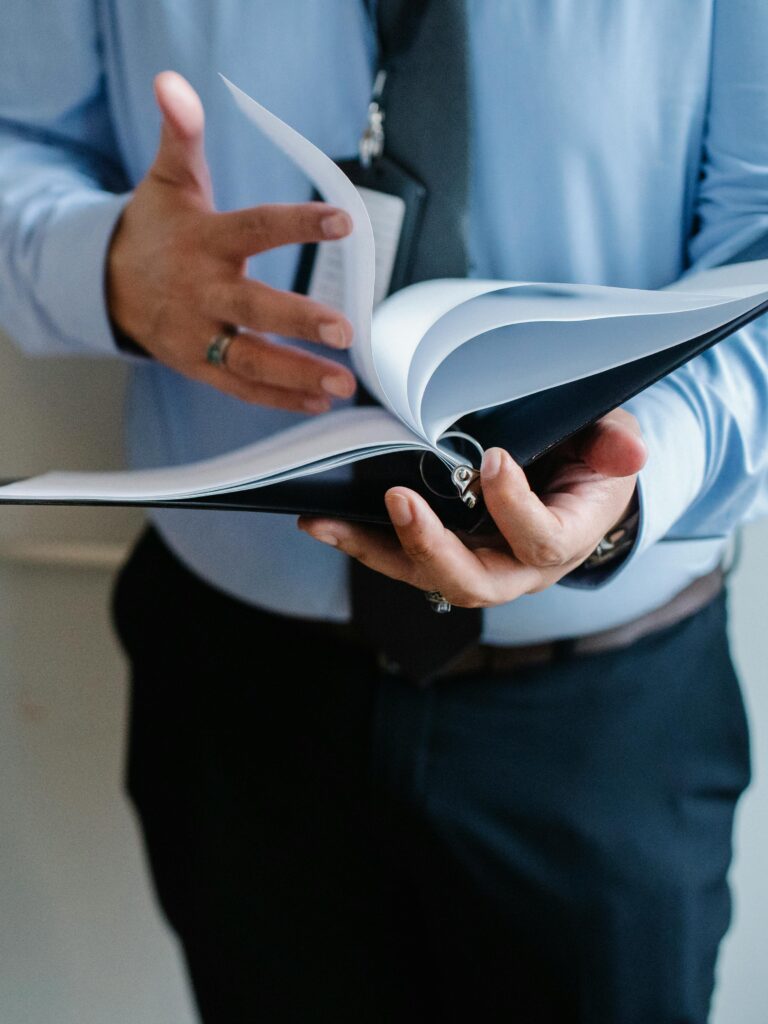 pexels photo 5668837 5668837 A business professional in a suit flips through documents indoors, emphasizing formal work settings.