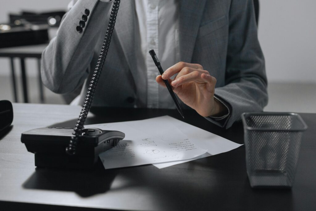 pexels photo 9068376 9068376 A business professional in a gray suit making notes with a pen while on a phone call.